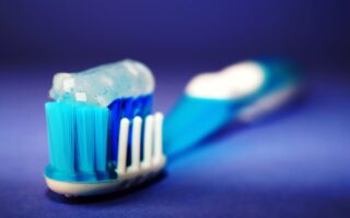Macro shot of a toothbrush with blue toothpaste and blurred background.