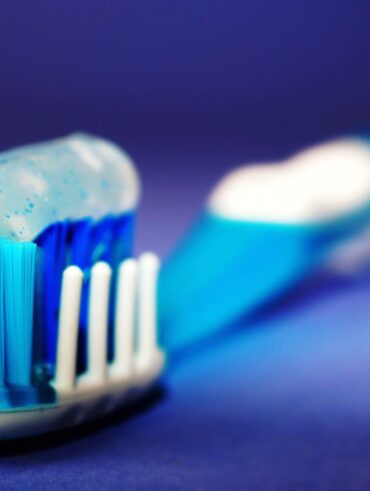 Macro shot of a toothbrush with blue toothpaste and blurred background.
