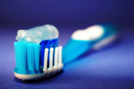 Macro shot of a toothbrush with blue toothpaste and blurred background.