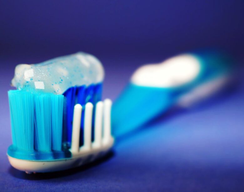 Macro shot of a toothbrush with blue toothpaste and blurred background.