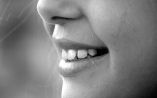 A monochrome close-up of a smiling face showcasing teeth and lips.