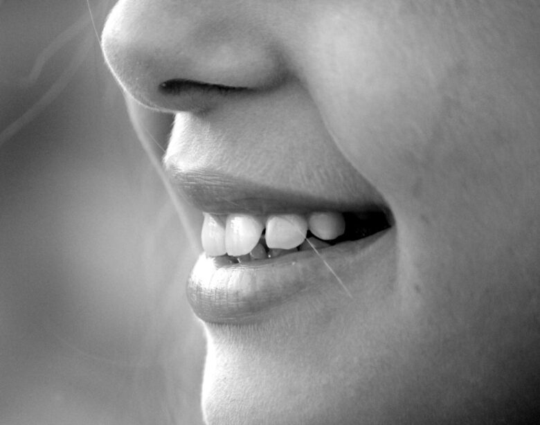 A monochrome close-up of a smiling face showcasing teeth and lips.